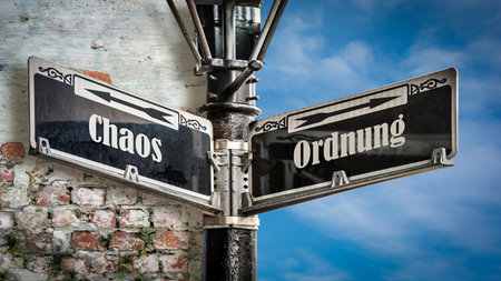 An image with a signpost pointing in two different directions in German. One direction points to order, the other points to chaos.の写真素材