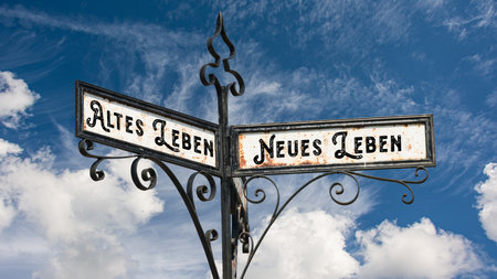 An image with a signpost pointing in two different directions in German. One direction points to New Life, the other points to Old Life.の写真素材