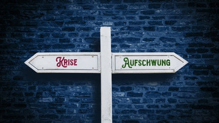 An image with a signpost pointing in two different directions in German. One direction points to upturn, the other points to crisis.の写真素材
