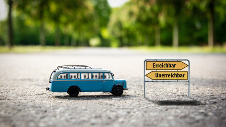 An image with a signpost pointing in two different directions in German. One direction points to...