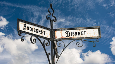 An image with a signpost pointing in two different directions in German. One direction points to...