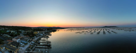 Panoramic view of a sunrise over the Thau lagoon and the oyster farms and their tables.の写真素材