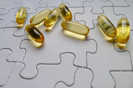 Several yellow transparent pills are randomly spread out on a white plain jigsaw puzzle, concept...