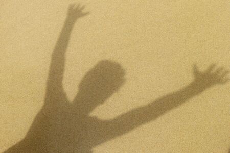 Shadow of adolescent male on sand, suggesting beach, summer, happiness, joyの写真素材