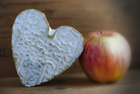 still life with a Norman cheese Neufchatel (PDO) and an apple, on wooden backgroundの写真素材