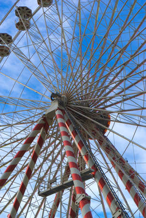 Low angle view of a ferris wheel against a blue skyの写真素材