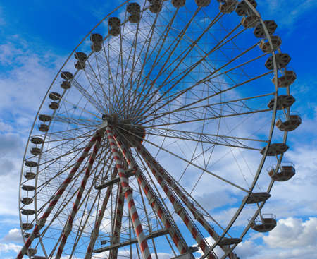 Low angle view of a ferris wheel against a blue skyの写真素材