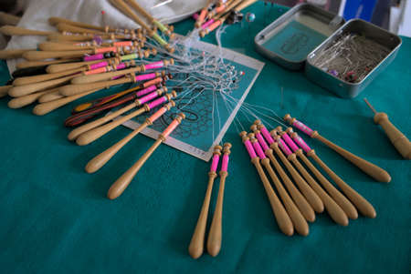 Lacemaker work in progress, close-up. Table, bobbins and thread.