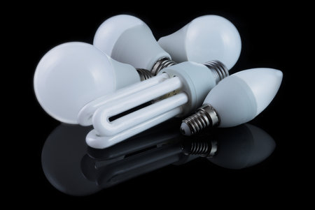 Energy-saving light bulbs of different shapes, illuminated, on a black background