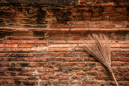 Vintage style broom put against the old brick wall.の写真素材