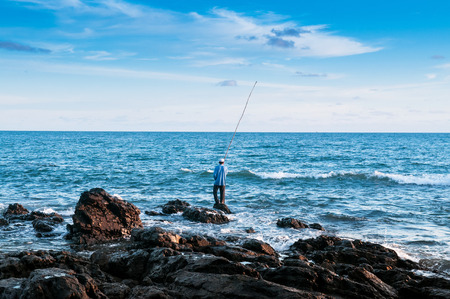 Local fisherman is fishing with bamboo fishing rod in the evening at Nui beach on Koh Lanta, Krabi, Thailandの写真素材
