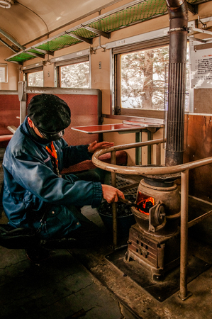 JAN 21, 2014 Aomori, Japan : Conductor put coals in potbelly stove on old classic vinatge train of Tsugaru railway at Goshogawara station, Famous sightseeing trian of Aomoriのeditorial素材