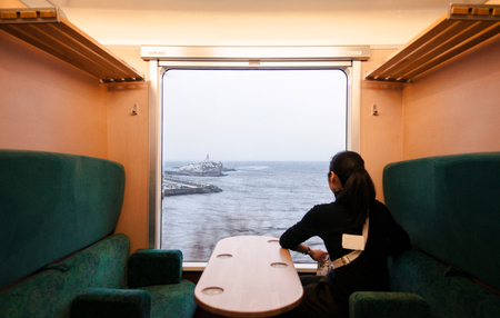JAN 21, 2014 Aoike, Japan : Interior of East Japan Railway Gono line resort Shirakami sightseeing train in winter. Female Passenger sit in private seat with Japan sea scenery.のeditorial素材