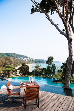 MAR 28, 2014 Phuket, Thailand : Dinner table by the pool with ocean view and beautiful big tree in Phuket, Thailandのeditorial素材