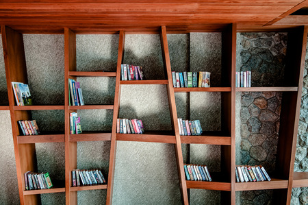 Books and textbooks on modern wooden bookshelf in libraryの写真素材