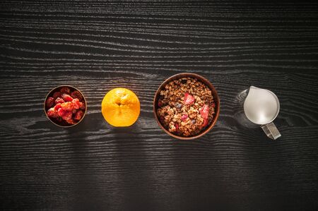 Healthy breakfast. granola muesli with fruits and milk in  wooden bowl on a wooden black background...