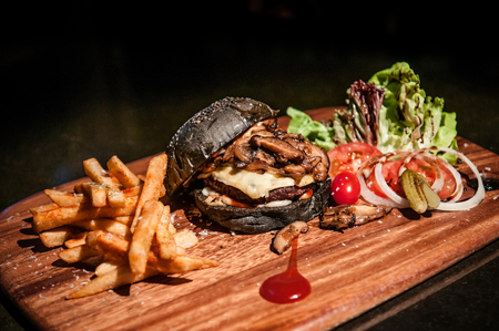 Beef charcoal black burger with french fries cheese, vegetable, sauceの写真素材