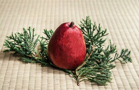 Fresh ripe red pear on pine leaf and tatami background, side angle shotの写真素材
