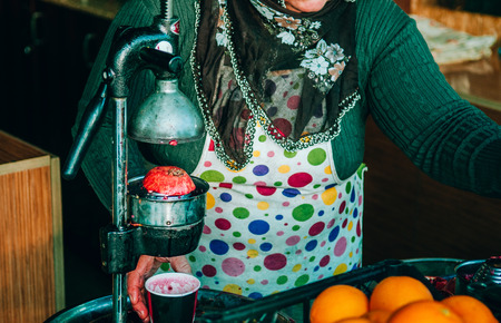 JAN 3, 2018 Goreme, Nevsehir, Turkey : Local Turkish seller squeezes fresh pomegranates to get juice. Rustic film look imageのeditorial素材