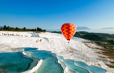 Hot air balloon flying over Travertine pools limestone terraces on beautifulday in Pamukkale, Denizili, Turkeyの写真素材