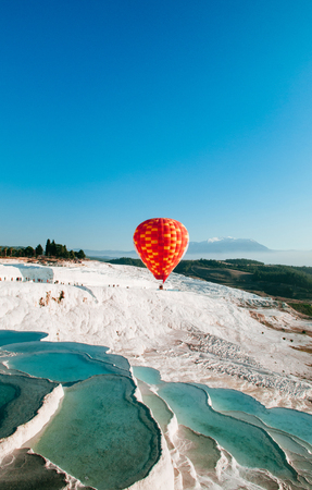 Hot air balloon flying over Travertine pools limestone terraces on beautifulday in Pamukkale, Denizili, Turkeyの写真素材