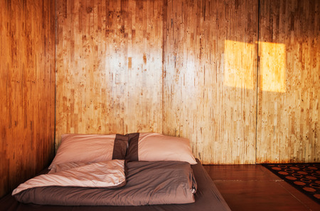 Warm cozy bedroom with simple futon on the floor, Log cabin house interiorの写真素材
