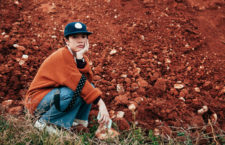 Young asian woman wearing sweater and street style clothes holding mobile phone  with nature red soil background with copy spaceの写真素材