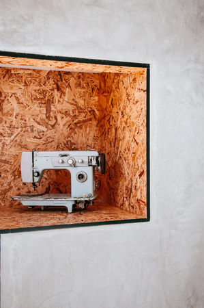 Light color vintage sewing machine on flakeboard background