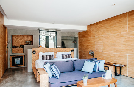 FEB 23, 2015 Kanchanaburi, Thailand : White contemporary loft hotel style bedroom with white linen high ceilling and vintage sofa couch, wooden wallのeditorial素材