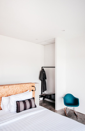 FEB 23, 2015 Kanchanaburi, Thailand : White contemporary hotel style bedroom with white linen high ceilling and modern coloured chairs, vertical shotのeditorial素材