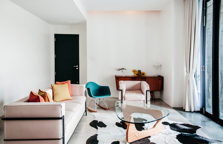 FEB 23, 2015 Kanchanaburi, Thailand : Beautiful modern retro furniture armchair sofa table interior with daylight - pastel color pillows, cow leather carpet in living roomのeditorial素材