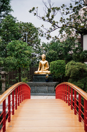 JUNE 27, 2014 - Kawasaki, Japan : Beautiful architecture landscape of Japanese garden, red bridge and golden Buddha statue of Kawasaki Daishi Templeのeditorial素材