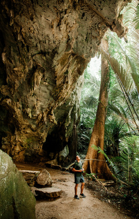 Young asian male photographer in forest cave. Travel lifestyle concept in nature forest. Thailandの写真素材