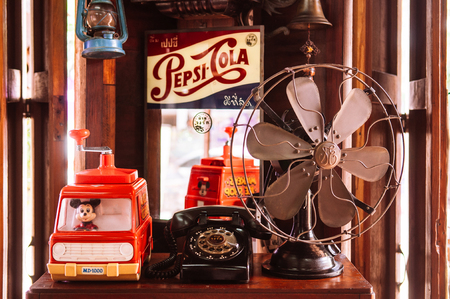 MAR 1, 2018 Uthaithani, Thailand : Vintage retro fan, toys, telephone and cola drink sign on wooden shelfのeditorial素材