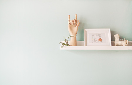 Wooden ball-jointed  hand photo frame and decorating ceramic doll and tillandsia plant on pastel blue wall backgroundの写真素材