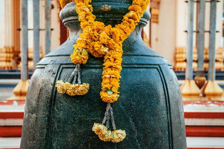 Traditional Thai Large bronze bell with yellow flower garland Wat Sangkat Rattana Khiri, ancient temple Uthai Thani, Thailand.の写真素材