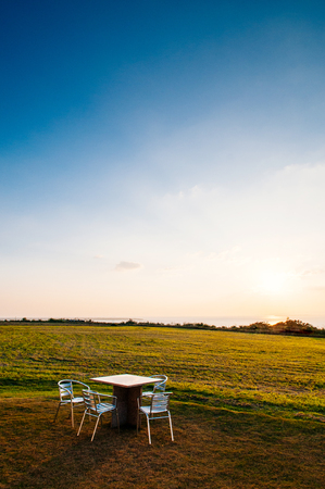 Wide Grass field by the ocean with picnic table at sunset or sunrise in Ishigaki island, Okinawa, Japanの写真素材