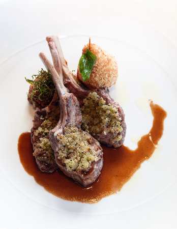Waiter serving grilled lamb chops with crust, gravy and deep fried potato, close up shotの写真素材
