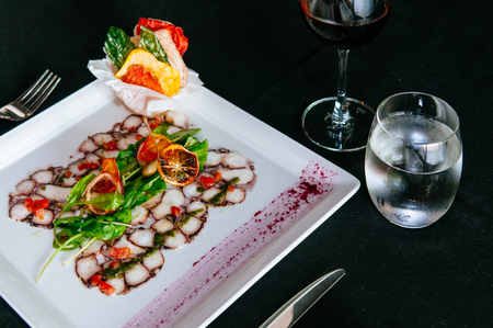 Fresh octopus carpacio with citrus spinach salad pesto balsamic dressing, fine dinning table settingの写真素材