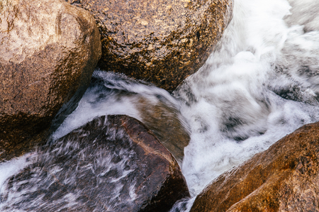 Close up details of Tropical river flowing rapid water and rocks landscape, slow shutter speed