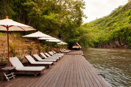 Resort style beach daybeds and white umbrellas by river Kwai, Kanchanaburi, Thailandのeditorial素材