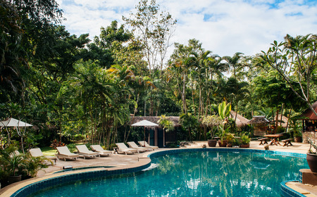 JUL 13,2013 Kanchanaburi, Thailand - Resort style beach daybeds and umbrellas by swiming pool in...