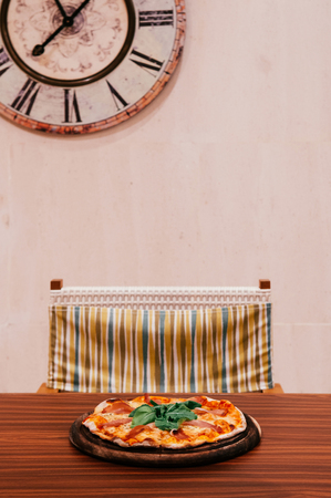 Italian margherita pizza with parma ham and basil on wood table in vintage style dining roomの写真素材