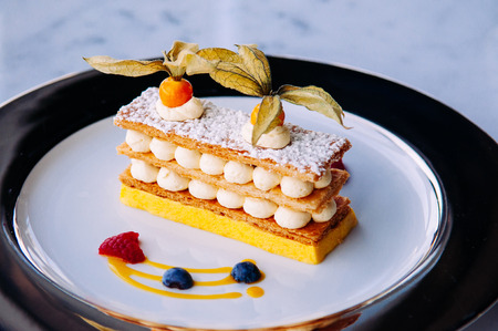 Beautiful dish of mango berries Millefeuilles French puff pastry on elegant plate on marble table