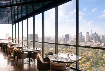 AUG 26, 2013 Bangkok, Thailand - Art deco interior dining room, vibrant desingn with glass wall Bangkok city center view, luxury diner table set and armchairsのeditorial素材