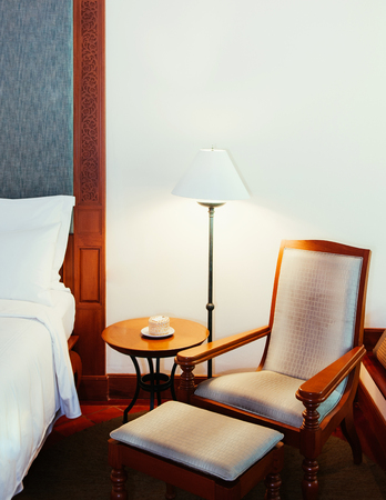 FEB 8, 2013 Phuket, Thailand - Old classic teak wood table, chair and lamp, bedroom with white wall - Asian vintage home Interior warm atmosphereの写真素材