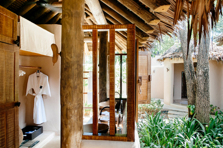 FEB 6, 2013 Phuket, Thailand - Thatched roof open air bathroom in garden with bath robe, tropical resort style interior with old wood and natural color fabric.のeditorial素材