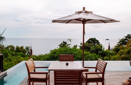 FEB 9, 2013 Phuket, THAILAND - Vacation Relaxation resort contemporary wooden dinner table by the infinity pool with ocean viewのeditorial素材