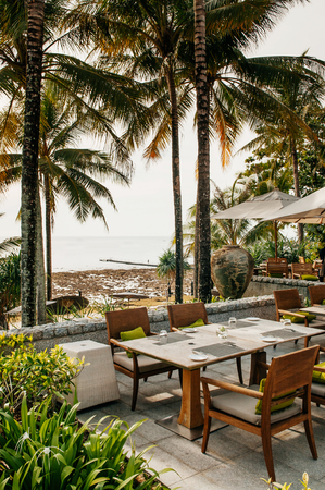 FEB 9, 2013 Phuket, THAILAND - Dinner table and chairs under umbrella in tropical coconut tree garden, outdoor dinning area.のeditorial素材