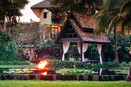 NOV 13, 2013 Samui, Thailand - Lotus pond in tropical garden with coconut tree and pavilion with fire torches, luxury resort landscapeのeditorial素材